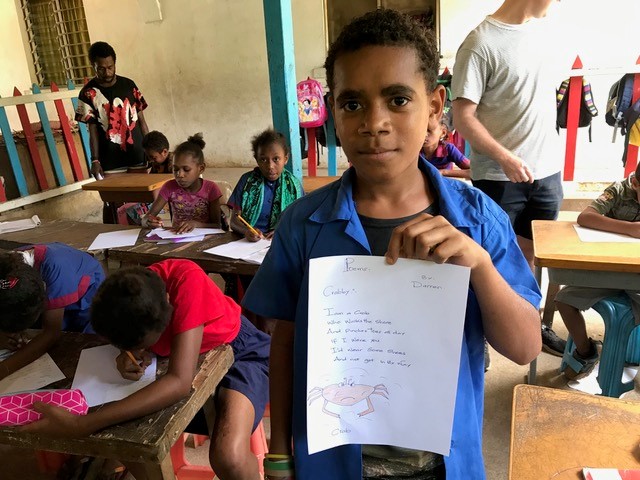 young boy holding up his work