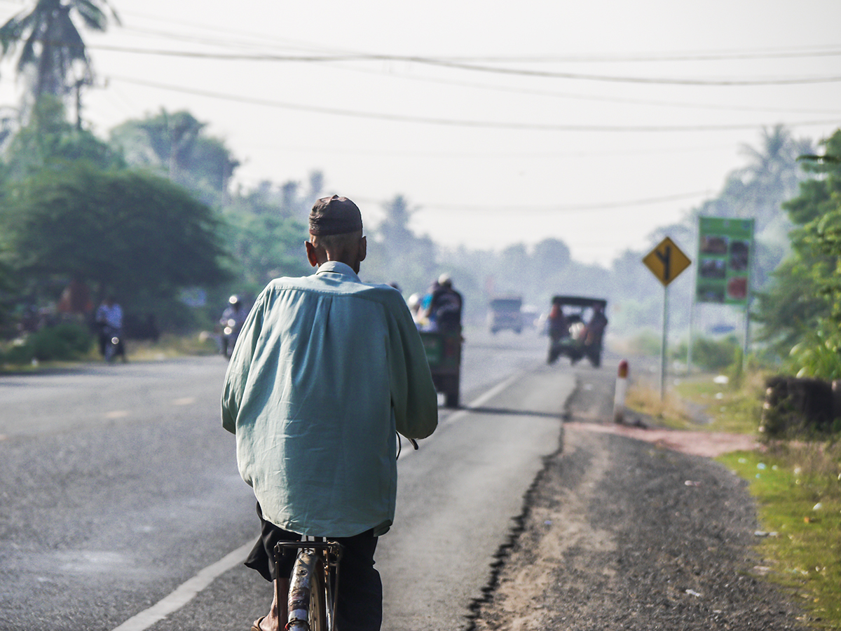 man riding bike alongside road