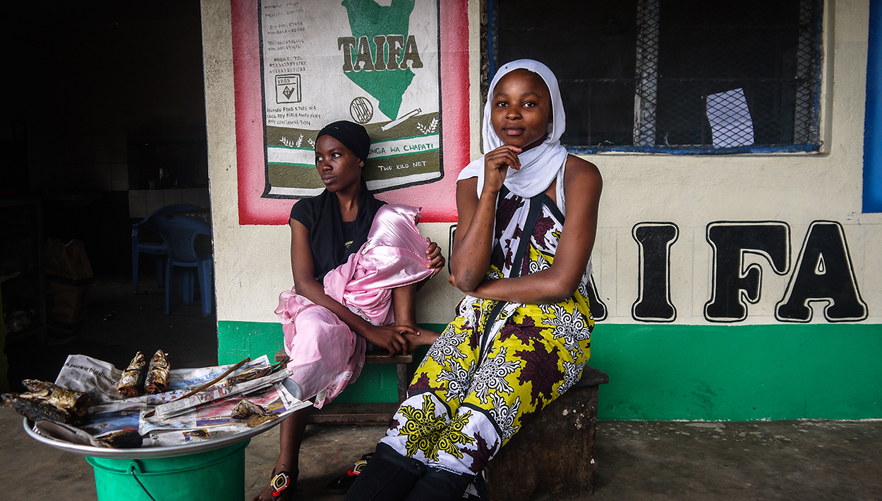 young Kenyan women sittng outside shop