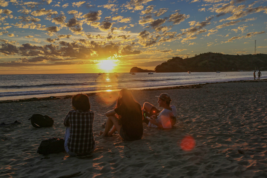 group sitting on the beach at sunset