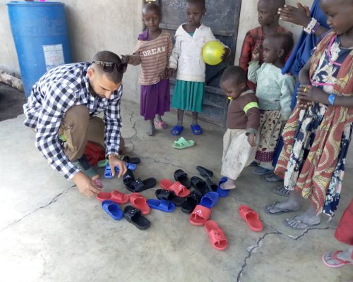 volunter giving new shoes to children on teaching project