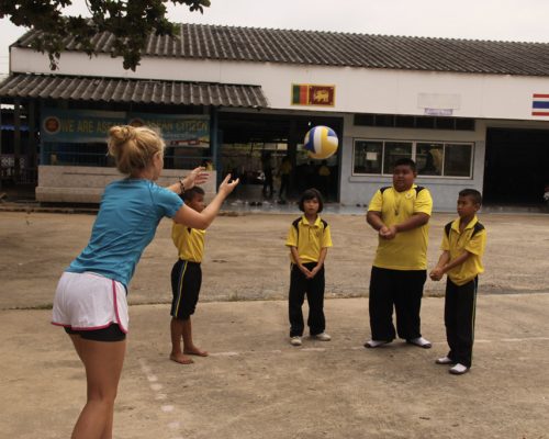 Students playing volleyball with participants