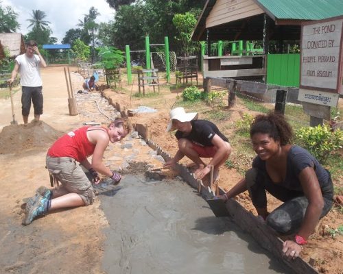 volunteers laying the path outside rural school cambodia